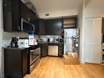 Chicago apartment for rent - A kitchen with black cabinets and a white fridge.