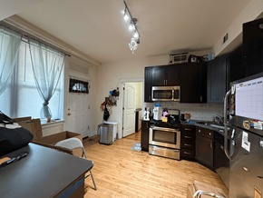Chicago apartment for rent - A kitchen with wooden floors and black cabinets.