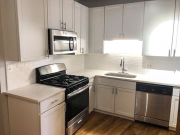 Chicago apartment for rent - A kitchen with white cabinets and a black stove top oven.