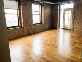 Chicago apartment for rent - A room with wooden floors and brick walls.