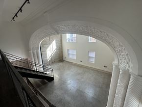 Chicago apartment for rent - A white arched hallway with a staircase on the left and a window on the right.