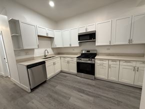 Chicago apartment for rent - A kitchen with white cabinets and a grey floor.