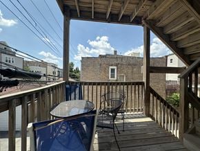 Chicago apartment for rent - A wooden deck with a table and chairs overlooking a brick building.