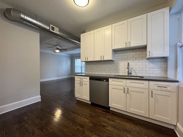 Chicago apartment for rent - A kitchen with white cabinets and a black countertop.