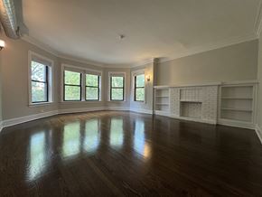 Chicago apartment for rent - A large empty room with wooden floors and a fireplace.