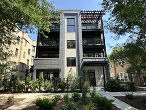 Chicago apartment for rent - A modern building with a black and white facade is surrounded by greenery.