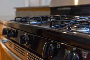 Chicago apartment for rent - A close up of a black gas stove with four burners and knobs for controls.
