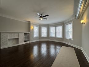 Chicago apartment for rent - A spacious room with a fireplace and a fan on the ceiling.