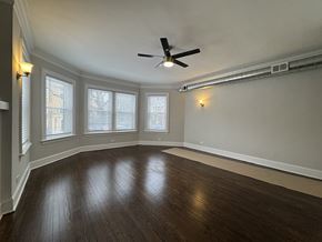 Chicago apartment for rent - A room with a ceiling fan and wooden flooring.