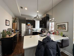 Chicago apartment for rent - A kitchen with a white counter top and a person in a black jacket sitting at the counter.