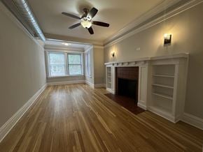 Chicago apartment for rent - A room with a fireplace and a ceiling fan.