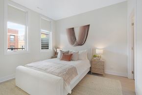 Chicago apartment for rent - A bedroom with a large bed and a window with a view of a building outside.
