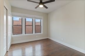 Chicago apartment for rent - A room with a ceiling fan and a window with a view of a brick building.