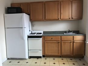Chicago apartment for rent - A kitchen with a white fridge, black microwave, and a white stove.