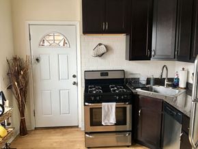 Chicago apartment for rent - A kitchen with a white door and black cabinets.