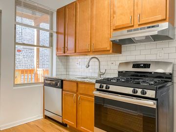Chicago apartment for rent - A kitchen with wooden cabinets and a stove top oven.