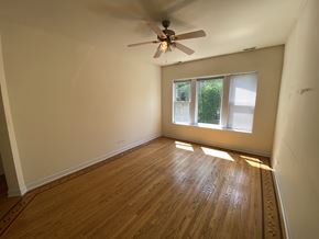Chicago apartment for rent - A room with a ceiling fan and wooden flooring.