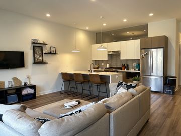 Chicago apartment for rent - A modern living room with a grey sofa and a kitchen in the background.