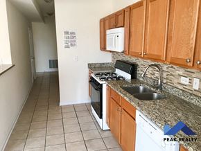 Chicago apartment for rent - a kitchen with wood cabinets and granite counter tops and a sink and stove
