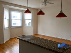 Chicago apartment for rent - an empty living room with three windows and a kitchen island