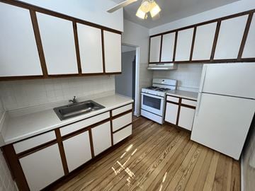 Chicago Il apartment for rent - A kitchen with white cabinets and a wooden floor.