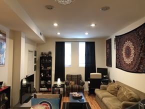 Chicago apartment for rent - A living room with a brown couch, a coffee table, and a large tapestry on the wall.