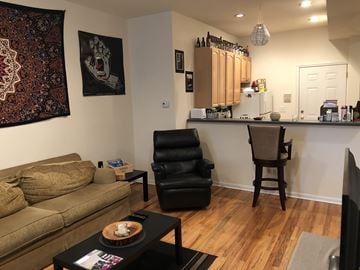 Chicago apartment for rent - A living room with a brown couch, a black chair, and a coffee table with a bowl of food on it.