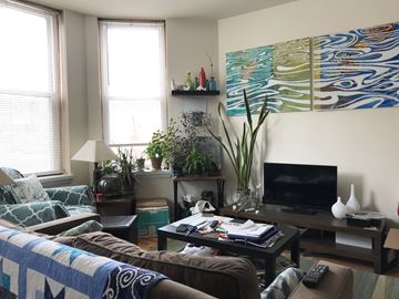 Chicago apartment for rent - A living room with a couch, a coffee table, a television, and a large painting on the wall.