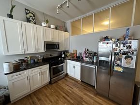 Chicago apartment for rent - A kitchen with white cabinets and a fridge filled with magnets.