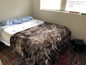 Chicago apartment for rent - A bed with a blue pillow and a black box on the floor.