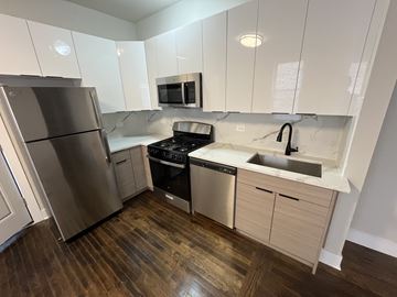 Chicago apartment for rent - A kitchen with a stainless steel refrigerator, microwave, oven, and sink.