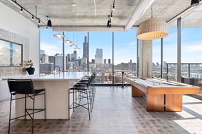 Chicago apartment for rent - a game room available to Sage West Loop's residents with a pool table and bar with chairs and a view of the Chicago skyline