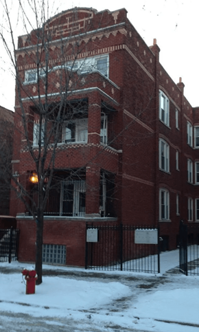 Chicago apartment for rent - A red brick building with a black fence and a red fire hydrant in front of it.