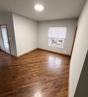 Chicago apartment for rent - A room with wooden floors and a window with blinds.