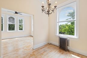 Denver apartment for rent - A room with a chandelier, a window with a view of trees, and a radiator on the floor.
