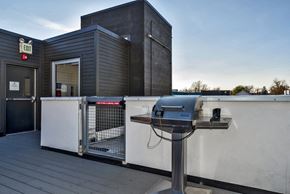 Denver apartment for rent - a grill on a patio next to a building with a dog gate