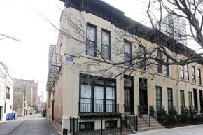 Chicago apartment for rent - A beige building with black railings and a black awning.