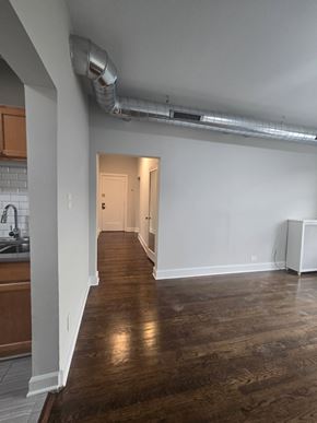 Chicago apartment for rent - A long hallway with a white wall and a white floor heater.