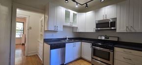 Chicago apartment for rent - A kitchen with white cabinets and black countertops.