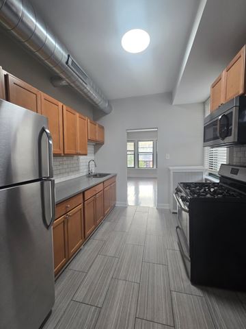 Chicago apartment for rent - A kitchen with a stainless steel refrigerator and black stove top oven.