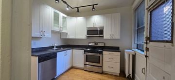 Chicago apartment for rent - A kitchen with white cabinets and black countertops.