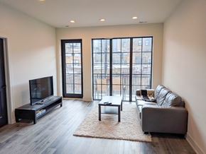 Chicago apartment for rent - A living room with a grey couch, a black coffee table, and a television.