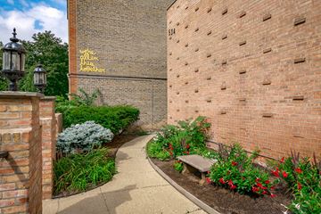 Chicago apartment for rent - a garden with flowers and a bench in front of a brick building