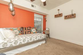 Baton Rouge apartment for rent - A bedroom with orange walls and a bed with a white comforter. at The Cove at State Street Apartments, Baton Rouge