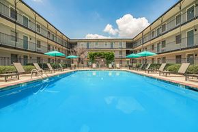 Baton Rouge apartment for rent - A large swimming pool in a resort with sun loungers and umbrellas. at The Cove at State Street Apartments, Baton Rouge, LA