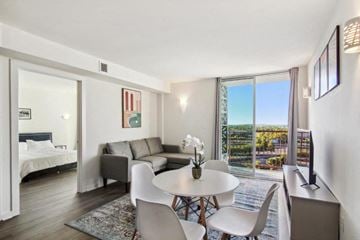 New Orleans apartment for rent - A living room with a white table and chairs, a couch, and a bed with a white headboard.