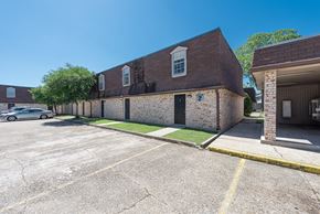 Baton Rouge townhouse for rent - A parking lot with a building on the right.