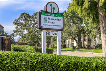 New Orleans apartment for rent - A sign for Whispering Palms apartments is displayed in front of a building.
