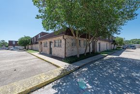 Baton Rouge townhouse for rent - A parking lot with a building and a tree in front.