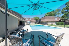 Baton Rouge townhouse for rent - A pool area with chairs and a blue umbrella.